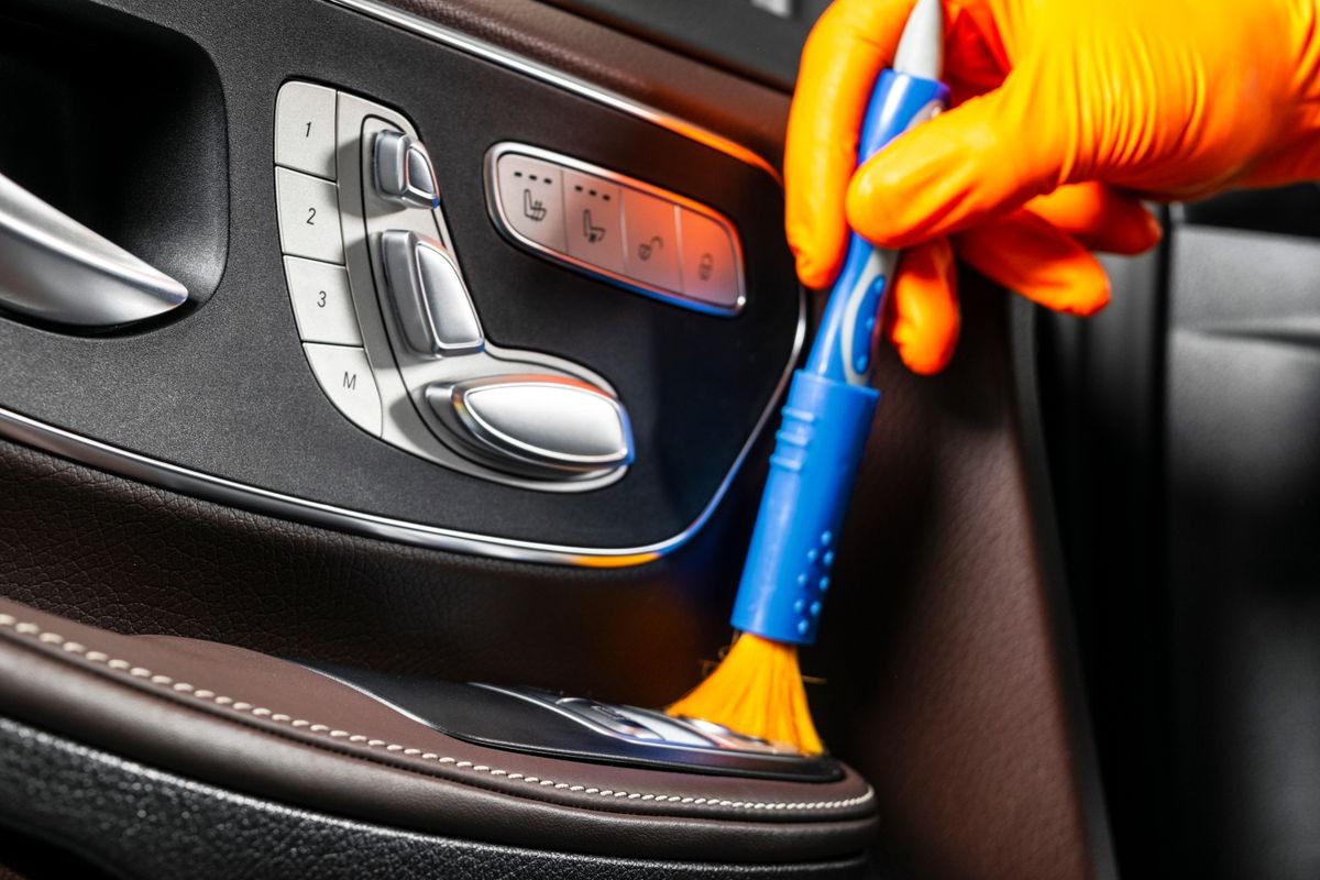 A man cleaning car with cloth and brush. Car detailing. Selective focus. Car detailing. Cleaning with brush. Worker cleaning. Brush and cleaning solution to clean.
